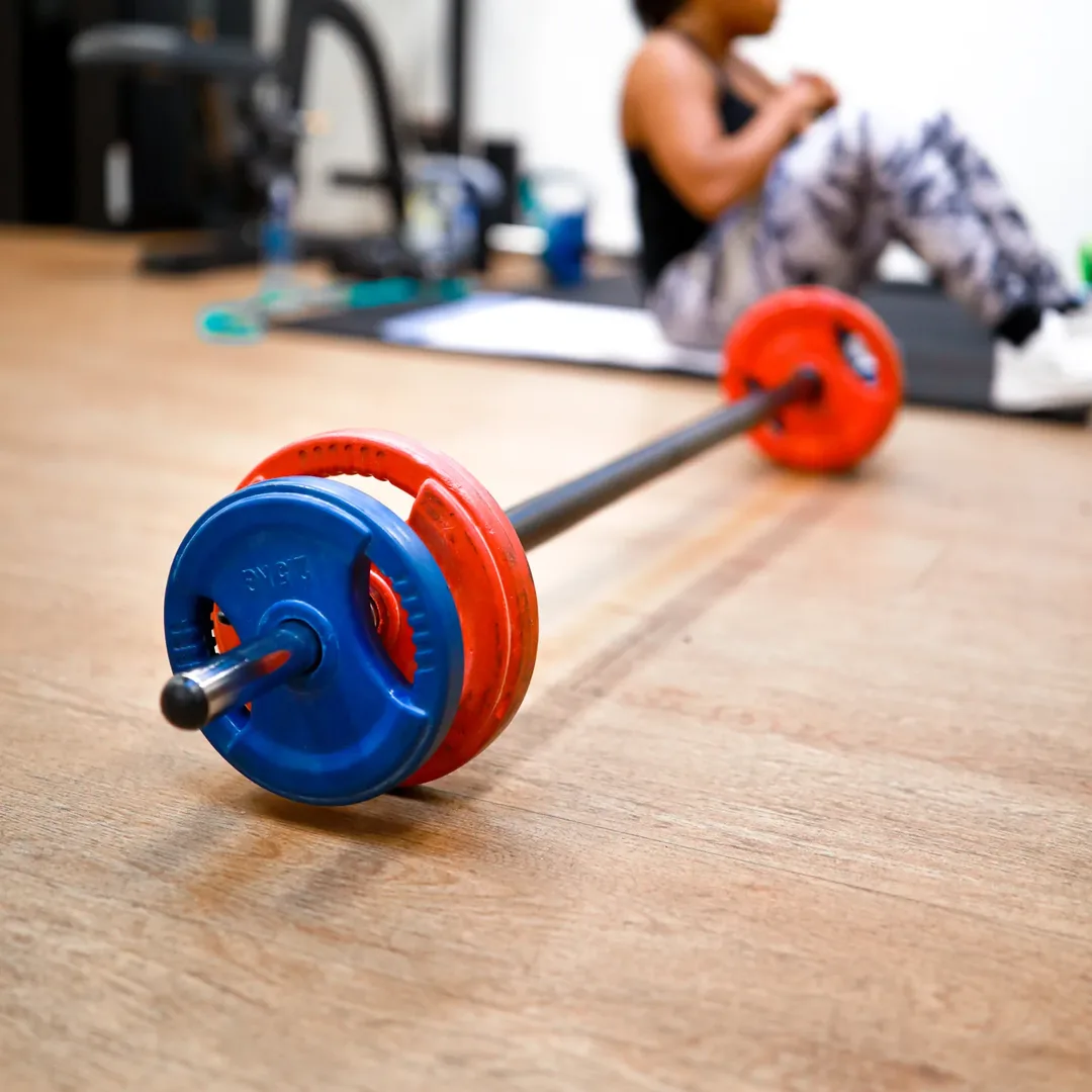 Een barbell op de trainingsvloer, met een lid dat op de mat traint
