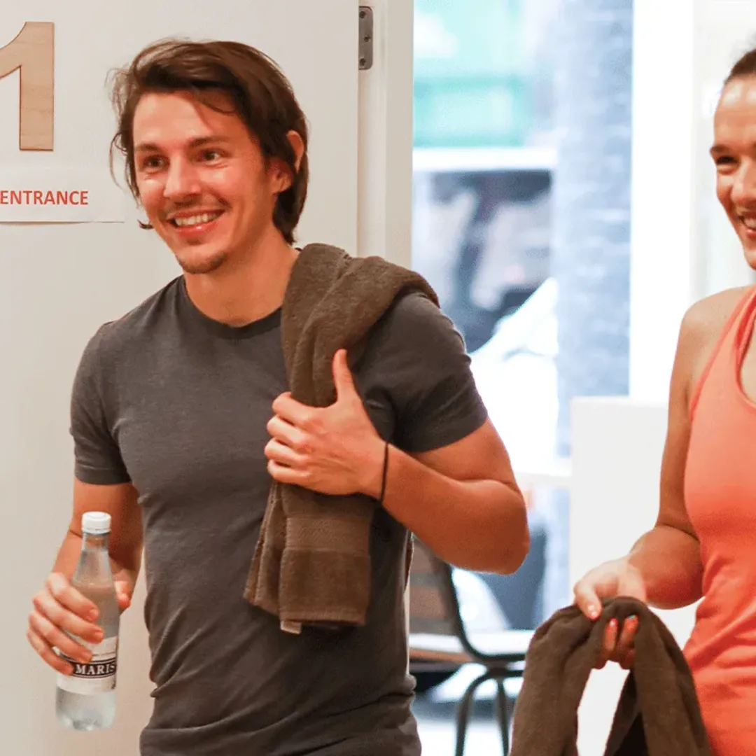 Twee leden komen lachend binnen bij de entree van de studio